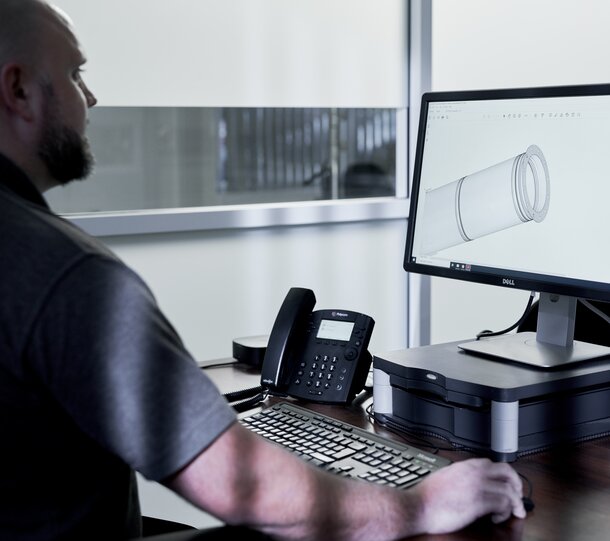 Schiedel Mitarbeiter arbeitet am PC mit der BIM Bibliothek und sieht sich gerade eine Zeichnung eines Edelstahl Rohres an