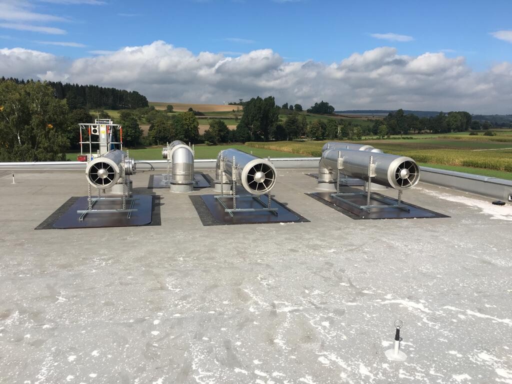 Mehrere Abgasschalldämpfer auf einem Dach eines Industriegebäudes